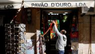 A man hangs football scarves in a store on the first day of the reopening after a country lockdown, amid the coronavirus disease (COVID-19) pandemic, in Lisbon, Portugal, April 5, 2021. REUTERS/Pedro Nunes/File Photo
