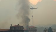 A helicopter drops water as the library at the University of Cape Town burns after a bushfire broke out on the slopes of Table Mountain in Cape Town, South Africa, April 18, 2021. REUTERS/Mike Hutchings