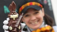 Belgian artisan chocolate maker Genevieve Trepant shows a chocolate bunny wearing a protective mask and holding a vaccine syringe called 