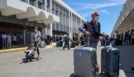 :Passengers arriving from Germany and Switzerland stand with their luggage outside the terminal of the Heraklion airport, as the country's tourism season officially opens, on the island of Crete, Greece, May 15, 2021. REUTERS/Stefanos Rapanis