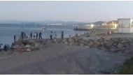 Migrants, who swam from Morocco to Spain, cross a fence on a beach in El Tarajal, Ceuta, Spain, May 17, 2021, in this still image from video obtained via social media. Ceuta Actualidad TV via Reuters 
