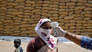 File photo: A healthcare worker checks the temperature of a rice mill worker during a coronavirus disease (COVID-19) vaccination drive at Bavla village on the outskirts of Ahmedabad, India, April 13, 2021. Reuters/Amit Dave/File Photo