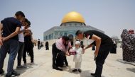 A Palestinian woman offers sweets to a boy before Friday prayer at the compound that houses Al-Aqsa Mosque REUTERS/Ammar Awad