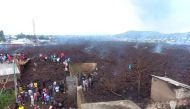 People walk near destroyed homes by lava deposited during the Mount Nyiragongo volcanic eruption near Goma, in the Democratic Republic of Congo May 23, 2021.REUTERS/Djaffar Al Katanty