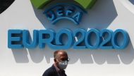 June 10, 2021 A man with a protective face-mask is seen in front of a Euro 2020 sign ahead of the opening match REUTERS/Guglielmo Mangiapane
