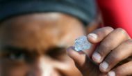A man shows an unidentified stone as fortune seekers flock to the village after pictures and videos were shared on social media showing people celebrating after finding what they believe to be diamonds, in the village of KWAHLATHI outside Ladysmith, in Kw