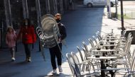A worker carries chairs at Les Arches bar in the city centre, as coronavirus disease (COVID-19) lockdown restrictions ease, in Lausanne, Switzerland April 19, 2021. REUTERS/Denis Balibouse/File Photo