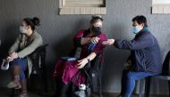 A teacher sprays a colleague's hands with sanitizer as they wait to receive a dose of a coronavirus disease (COVID-19) vaccine during a vaccine rollout for teachers in Meyerton, south of Johannesburg, South Africa June 23, 2021. (REUTERS/Siphiwe Sibeko)