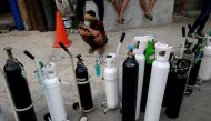 Firmansyah, a 52-year-old man, squats while queuing to refill oxygen tanks for his neighbor who has breathing problems as Indonesia experiences an oxygen supply shortage amid a surge of coronavirus disease (COVID-19) cases, at a filling station in Jakarta