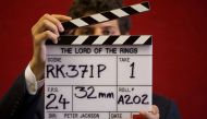 A gallery assistant poses for a photograph with a clapper board used in the filming of the Lord of the Rings film 'Return of the King' in Bonhams auction house in London July 31, 2014. REUTERS/Neil Hall