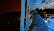 People are evacuated on a ferry as a wildfire burns in the village of Psaropouli, on Evia island, Greece, on August 8, 2021. Reuters/Alexandros Avramidis
