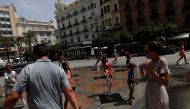 Three french tourist families cool off in a fountain at the Las Tendillas square, as a heatwave hits Spain, in Cordoba, southern Spain, August 14, 2021. REUTERS/Jon Nazca