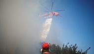 A firefighting helicopter makes a water drop as a wildfire burns in the village of Markati, near Athens, Greece, August 16, 2021. REUTERS/Alkis Konstantinidis