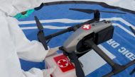 A medical worker wearing personal protective equipment (PPE) takes a box of medical supplies that is being delivered with a drone on the deck of a passenger ship owned by the state-owned shipping company PT PELNI, KM Umsini, which has been modified as an 