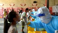 Medical workers wearing protective suits take swabs from primary school students at a nucleic acid testing site, following new cases of the coronavirus disease (COVID-19), in Fuzhou, Fujian province, China September 15, 2021. cnsphoto/via REUTERS