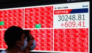 Men wearing protective face masks amid the coronavirus disease (COVID-19) outbreak, is reflected on a window of a building near an electronic board displaying Japan's Nikkei Index outside a brokerage in Tokyo, Japan, September 24, 2021. REUTERS/Kim Kyung-
