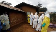 A healthcare worker who volunteered in the Ebola response, stands with decontamination gear as his colleague prepare to enter a house where a woman, is suspected of dying of Ebola in the Eastern Congolese town of Beni in the Democratic Republic of Congo, 