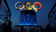 People wearing face masks following the coronavirus disease (COVID-19) outbreak are seen near the lit-up Olympic rings at top of the Olympic Tower, a year ahead of the opening of the 2022 Winter Olympic Games, in Beijing, China February 4, 2021. REUTERS/T