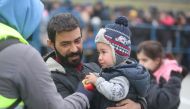 A child holds an apple during the distribution of humanitarian aid among migrants near Bruzgi - Kuznica checkpoint on the Belarusian-Polish border in the Grodno region, Belarus November 17, 2021. Leonid Scheglov/BelTA