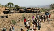 Villagers return from a market to Yechila town in south central Tigray walking past scores of burned vehicles, in Tigray, Ethiopia, July 10, 2021. REUTERS/Giulia Paravicini.