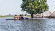 South Sudanese men navigate a canoe through flood waters in Bentiu in Unity State, South Sudan as seen in this image taken by Doctors Without Borders (MSF) on November 20, 2021. Picture taken November 20, 2021. Njiiri Karago/Medecins Sans Frontieres/Handout via REUTERS