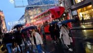 Shoppers hold umbrellas as they walk, following the outbreak of the coronavirus disease (COVID-19), at Oxford Street in London, Britain December 16, 2020. REUTERS/Toby Melville/File Photo GLOBAL BUSINESS WEEK AHEAD