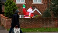 A man carrying shopping bags walks past a partially deflated blow-up Santa Claus amid the coronavirus disease (COVID-19) pandemic, in London, Britain December 20, 2021. REUTERS/Kevin Coombs
