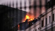 Flames and smoke rise over the roof of the National Assembly building as the fire at the parliament flared up again, in Cape Town, South Africa, January 3, 2022. Picture taken through a fence. REUTERS/Sumaya Hisham