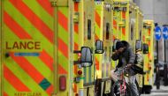 A man cycles between ambulances parked outside of the Royal London Hospital in London, Britain, January 7, 2022. Reuters/Toby Melville/File Photo