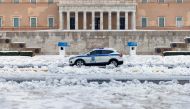A police car drives past the Greek parliament building, following heavy snowfall in Athens, Greece, January 25, 2022. REUTERS/Alkis Konstantinidis