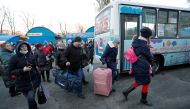 People walk to board a bus during the evacuation of local residents to Russia, in the rebel-controlled city of Donetsk, Ukraine February 19, 2022. Reuters/Alexander Ermochenko
 
