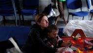 A woman rests with her son after fleeing Russia's invasion of Ukraine, at a refugee shelter in Beregsurany, Hungary, March 5, 2022. Reuters/Bernadett Szabo
 
