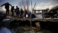 People file across a makeshift river crossing below a destroyed bridge as they flee from advancing Russian troops whose attack on Ukraine continues in the town of Irpin outside Kyiv, Ukraine, March 8, 2022. REUTERS/Thomas Peter

