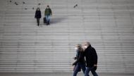 People, wearing protective face masks, walk past the steps near the Grande Arche at the financial and business district of La Defense in Puteaux near Paris, France, January 31, 2022. Reuters/Sarah Meyssonnier/File Photo