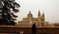 A man walks his dog near Almudena Cathedral, as storm Celia blew sand from the Sahara desert over Madrid, Spain, March 15, 2022. REUTERS/Susana Vera