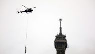 A helicopter flies next to the Eiffel Tower to install a new telecom transmission TDF (TeleDiffusion de France) antenna on its top, in Paris, France, March 15, 2022. REUTERS/Sarah Meyssonnier