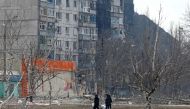 Local residents walk near a residential building which was damaged during Ukraine-Russia conflict in the besieged southern port city of Mariupol, Ukraine March 18, 2022. REUTERS/Alexander Ermochenko