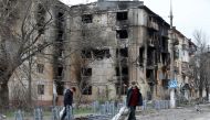 People walk past a residential building, which was heavily damaged during Ukraine-Russia conflict in the southern port city of Mariupol, Ukraine April 18, 2022. REUTERS/Alexander Ermochenko/File Photo