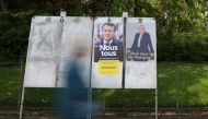 A woman walks past official campaign posters of French presidential election candidates Marine le Pen, leader of French far-right National Rally (Rassemblement National) party , and French President Emmanuel Macron, candidate for his re-election, displayed on an official billboard in Cambrai, France, April 19, 2022. REUTERS/Pascal Rossignol