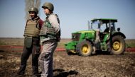 Yuri and Oleksiy, Ukrainian farmers wearing body armours and helmets, work at the topsoil in a field, amid Russia's invasion of Ukraine, in Zaporizhzhia region, Ukraine April 26, 2022. REUTERS/Ueslei Marcelino