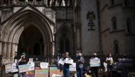 Demonstrators display placards during a protest outside the Royal Courts of Justice whilst a legal case is heard over halting a planned deportation of asylum seekers from Britain to Rwanda, in London, Britain, June 13, 2022. Reuters/Henry Nicholls