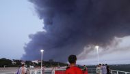 Beachgoers react, as smoke produced by wildfires in La Teste-de-Buch forest billows, Arcachon, France, July 18, 2022. REUTERS/Pascal Rossignol