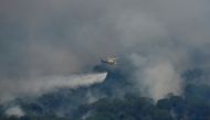 A helicopter throws water over a wildfire, as the country experiences a heatwave, in Cebreros, Avila, Spain, July 20, 2022. (REUTERS/Borja Suarez)