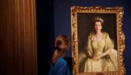 A staff member of the Royal Collection Trust poses for a photograph next to a painting known as the Wattle Portrait and is part of, Platinum Jubilee: The Queen’s Coronation exhibition at Windsor Castle, Windsor, Britain, July 6, 2022. REUTERS/Peter Nicholls
