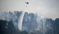 A Czech army helicopter helps to extinguish a forest fire, during a heatwave, close to the German-Czech border near Schmilka, Germany, July 26, 2022. REUTERS/Matthias Rietschel
