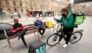 File Photo: Delivery riders wait for orders at Universitat square in Barcelona, Spain, February 26, 2021. (REUTERS/Albert Gea)