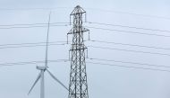 A wind turbine and an electricity pylon are seen in Finedon, Britain, March 30, 2022. REUTERS/Andrew Boyers


