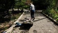 A man pulls a cart as he cleans his yard after a night shelling, as Russia's attack in Ukraine continues, in Bakhmut, Donetsk region, Ukraine August 21, 2022. REUTERS/Ammar Awad