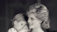 Young Prince Harry tries to hide behind his mother, Britain's Princess Diana, during a morning picture session at Marivent Palace, August 9, 1988. REUTERS/Hugh Peralta/File Photo