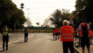 Police officers and media look on as the 80-meter tall obelisk is knocked down, during the dismantling of the Soviet WWII victory monument, in Riga, Latvia August 25, 2022. REUTERS/Ints Kalnins